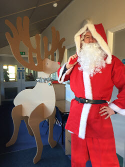 Father Christmas in red outfit next to a Caps Cases cardboard reindeer